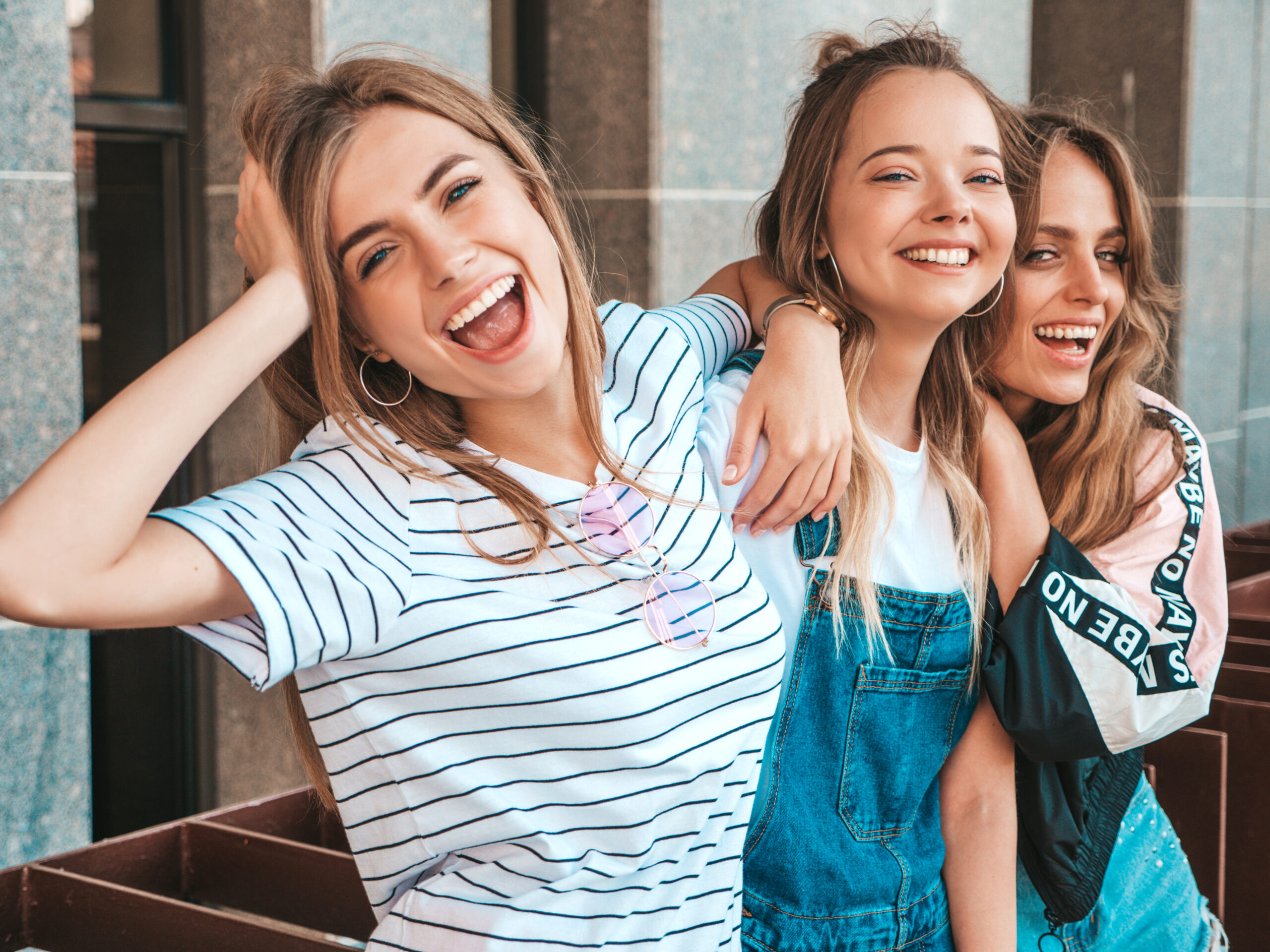 Portrait of three young beautiful smiling hipster girls in trendy summer clothes. Sexy carefree women posing on the street background.Positive models having fun